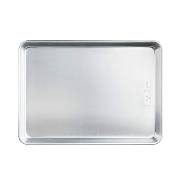 Delicata squash slices roasting on a baking sheet, showing the beginnings of golden edges.