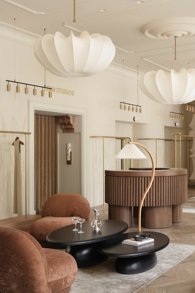 Sculptural white pendant lights hanging above a modern reception area with curved wooden furniture.