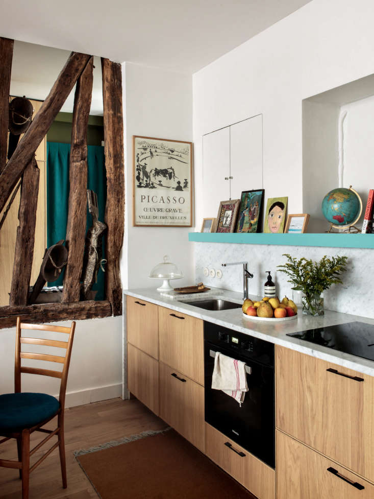 Kitchen featuring white cabinets, a grey marble countertop, and integrated wall shelving niches.