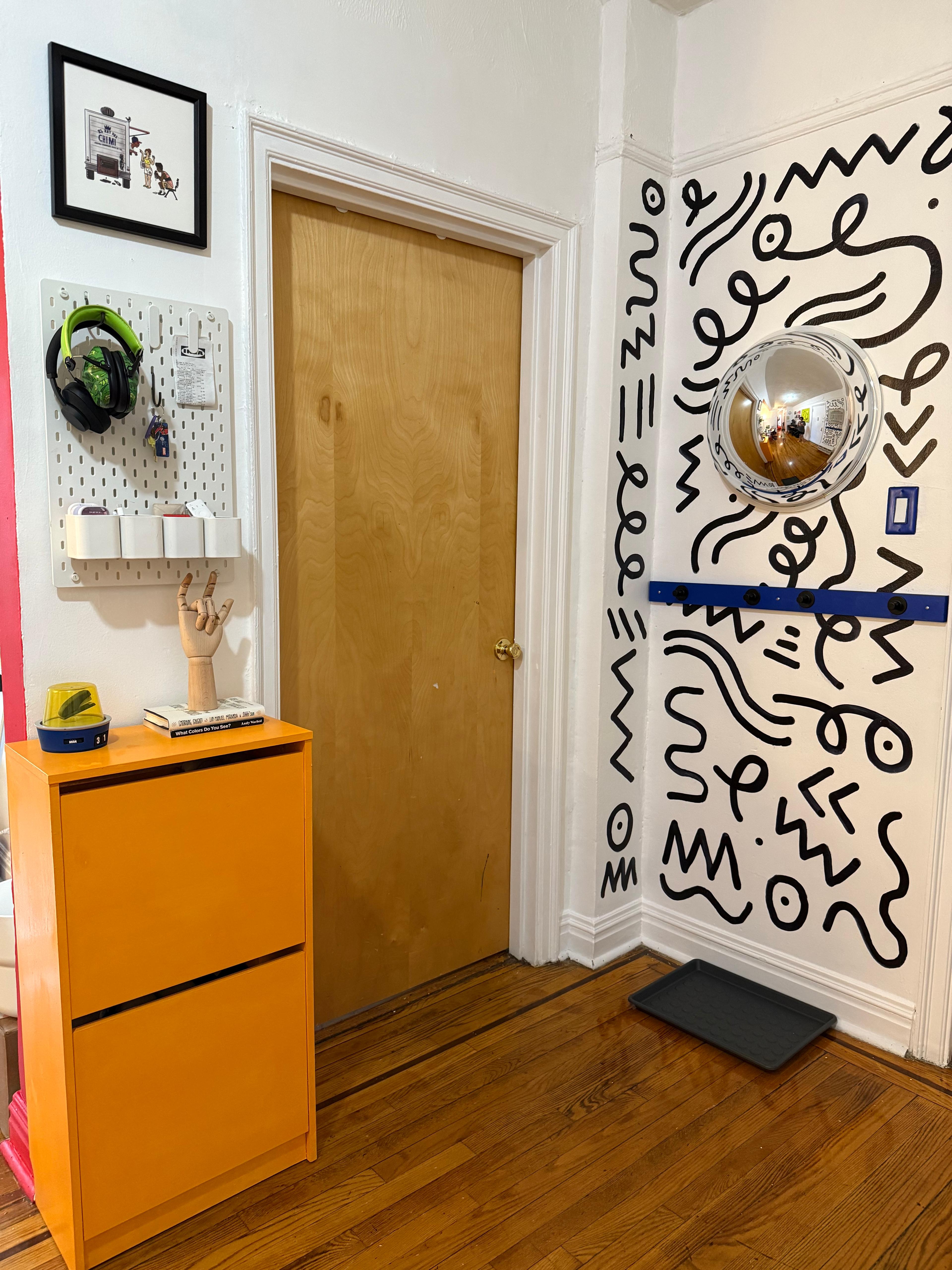 A functional entryway storage unit with a drawer and multiple hooks at varying heights.