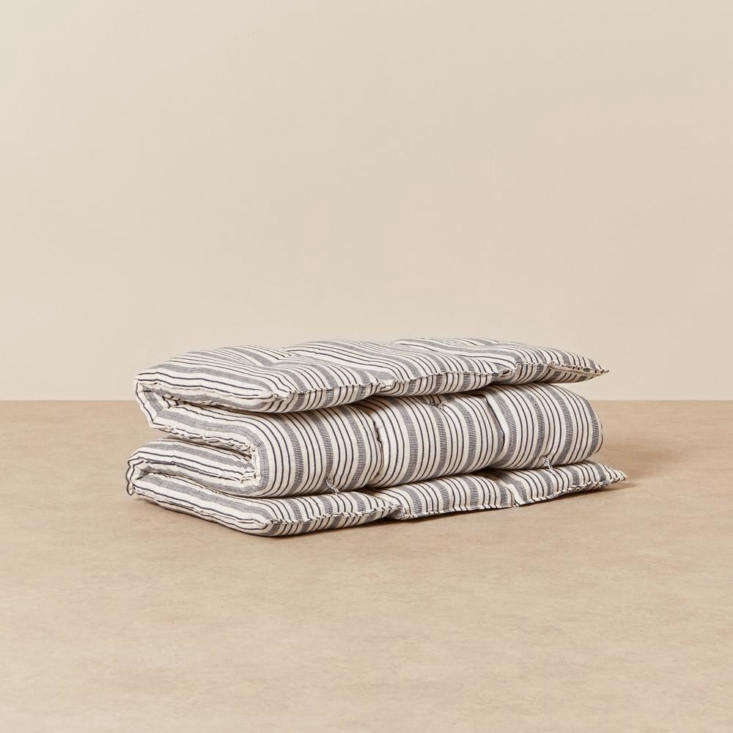 A striped kapok mattress bedroll providing extra texture and depth to a seating area.