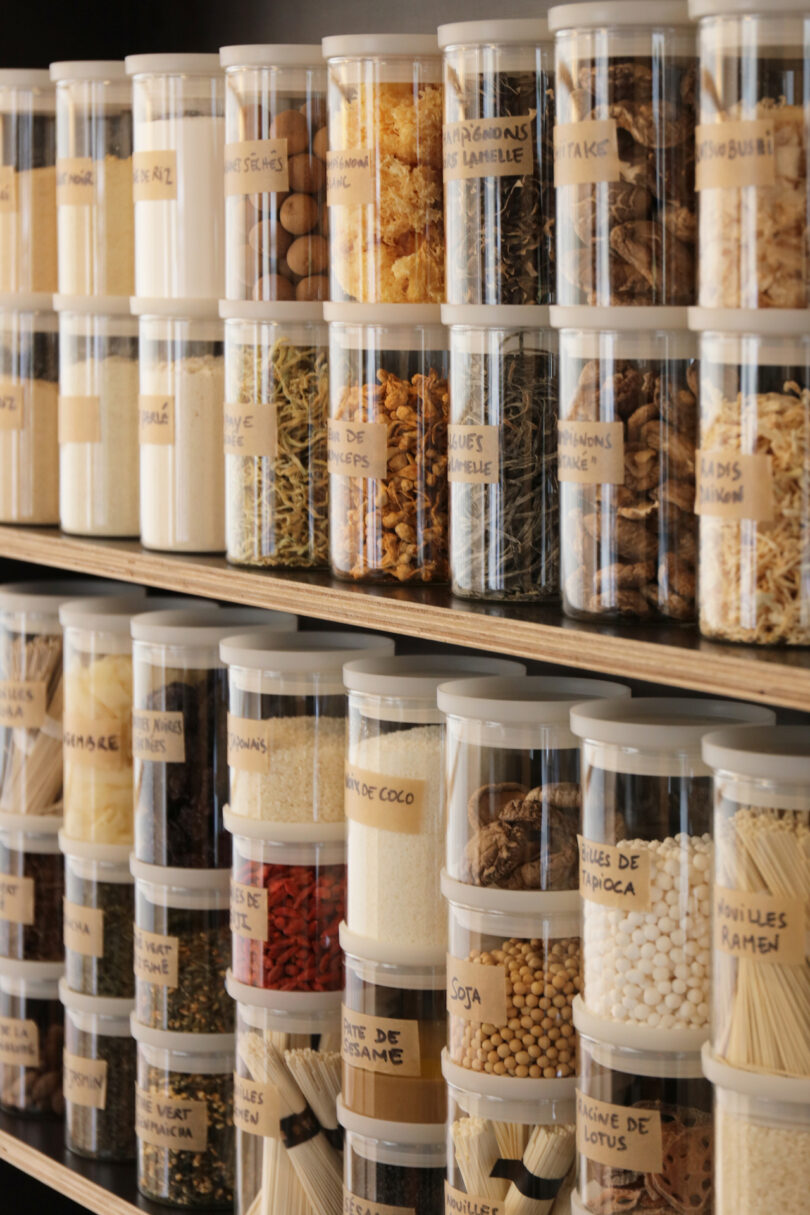 Neatly organized jars of spices and grains on minimalist shelves