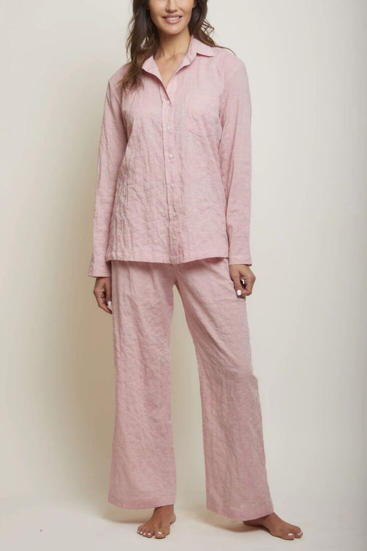 A woman wearing a pink organic Japanese cotton pajama set with white piping.