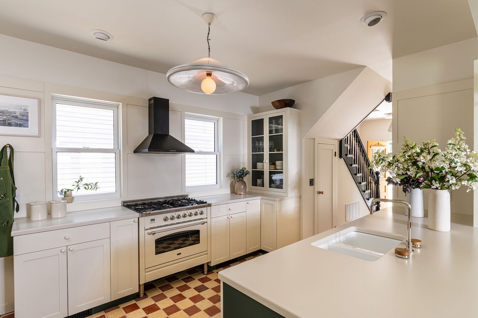 Vintage-inspired kitchen with custom Shaker cabinets, a large island, and reclaimed checkerboard tile flooring.