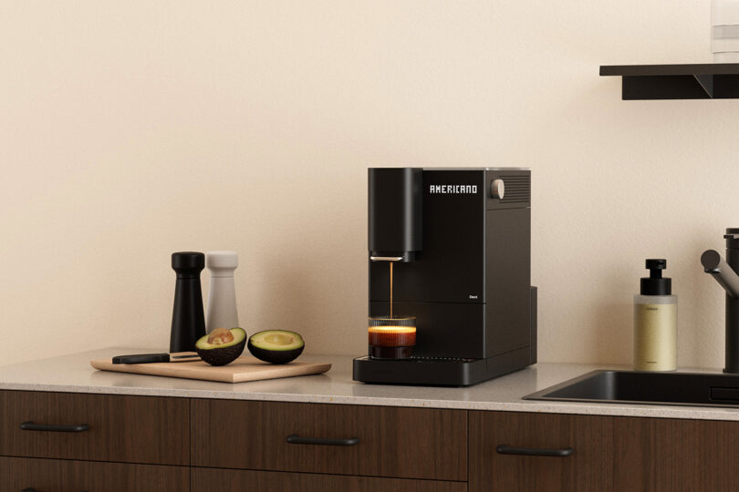 Close-up of the Terra Kaffe Demi's digital interface displaying 'AMERICANO' as it pours coffee into a cup.