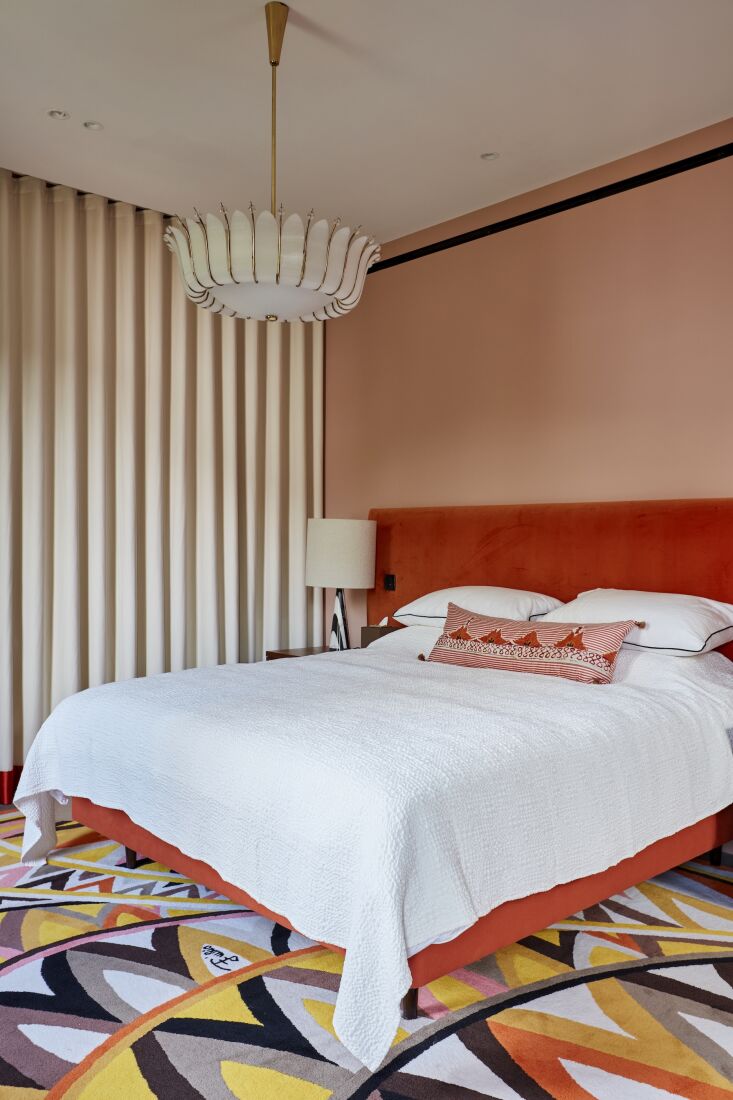 A bedroom with vibrant patterns and a flower-shaped vintage glass ceiling light fixture.