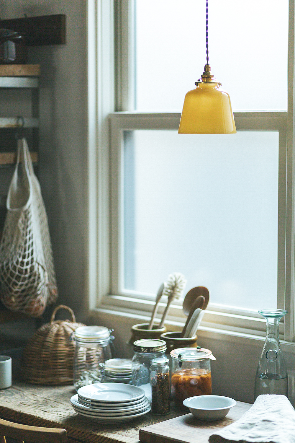 A Baba Glass pendant light featuring hand-blown milk glass and brass fittings with a twisted cord.