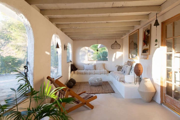 Built-in L-shaped sofa on a desert porch with French doors leading to the living room.