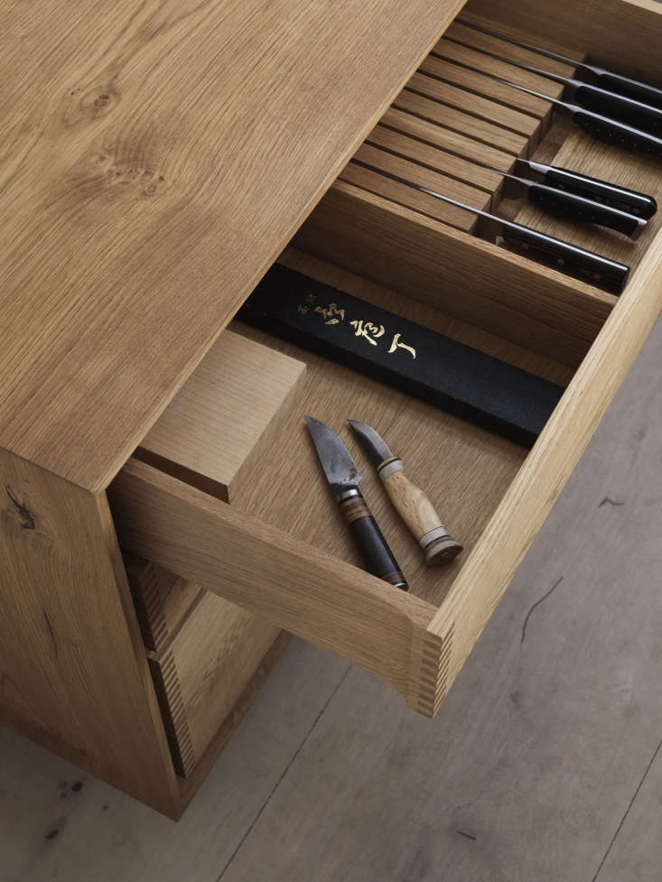 A custom wooden drawer insert holding a professional set of 10 to 12 kitchen knives.
