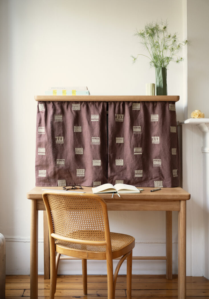 The Veil Desk in solid white oak featuring a fabric curtain to hide office equipment.