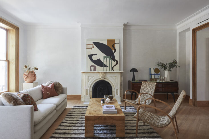 Restored parlor living room with a historic fireplace, original woodwork, and Diamond veneer plaster walls.