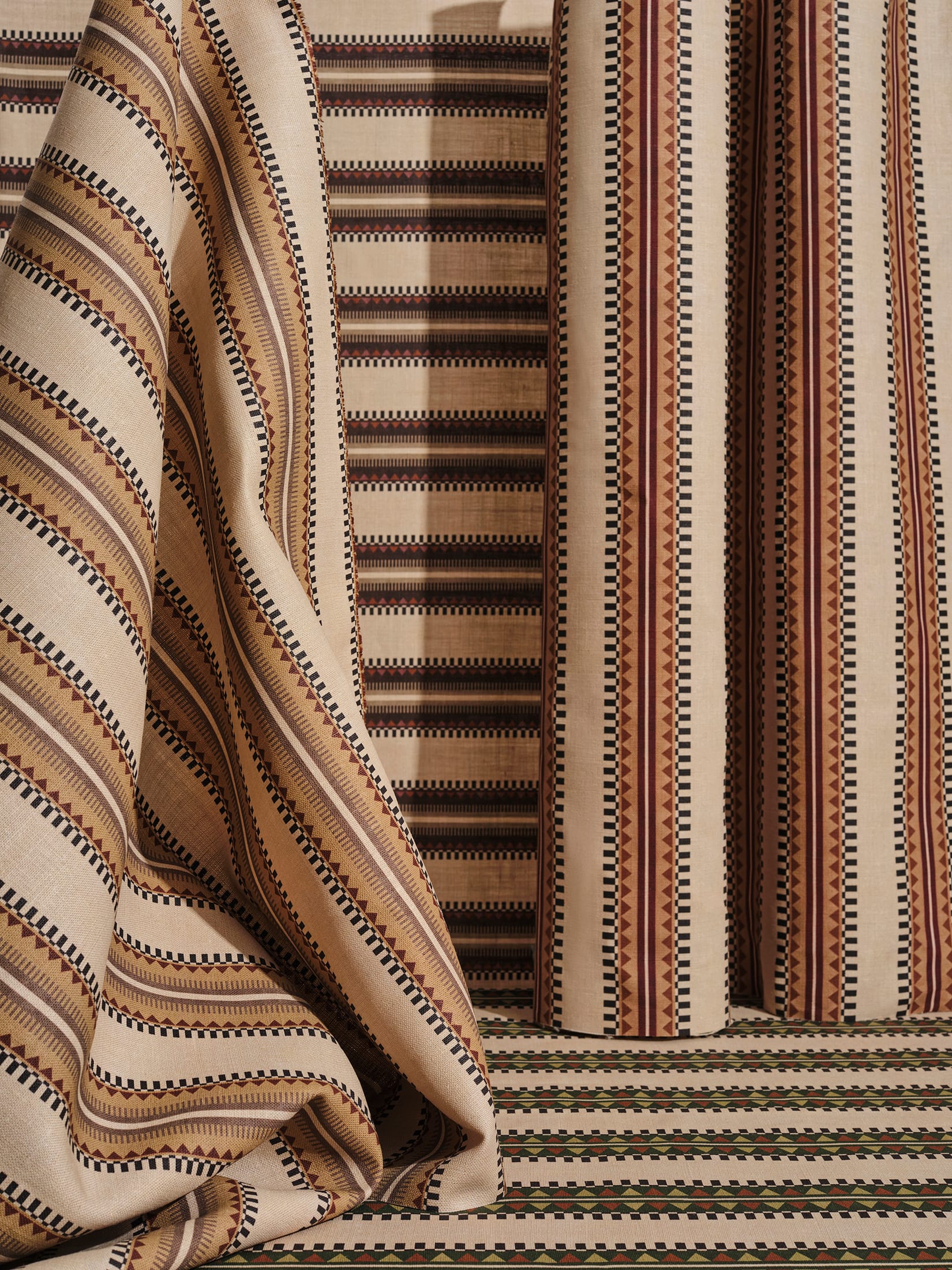 An arrangement of FÖLKE wallpaper and textile swatches showcasing coordinated color palettes and patterns.