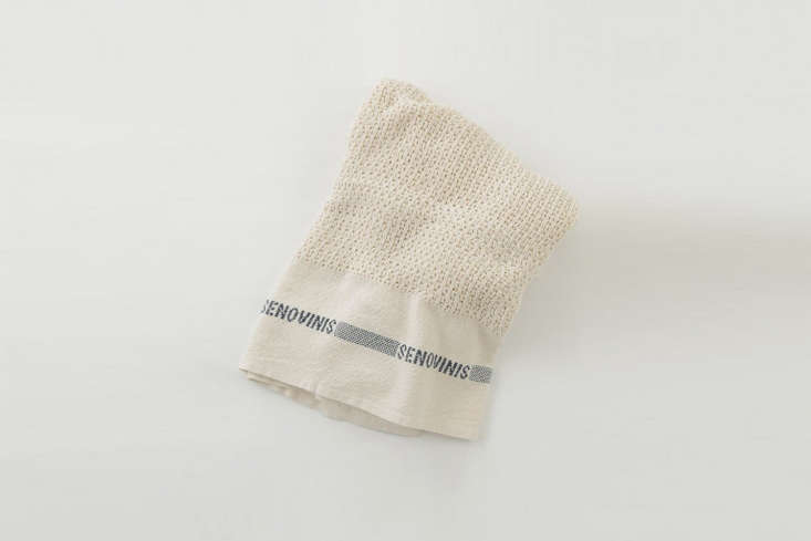 A lightweight cotton blanket with a textured weave folded on a bed.