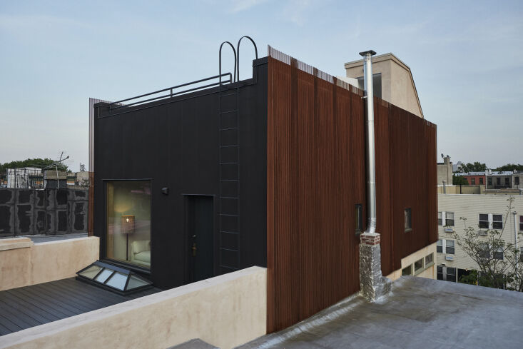 Top floor of a townhouse clad in black corrugated steel and a weathered-steel rain screen.