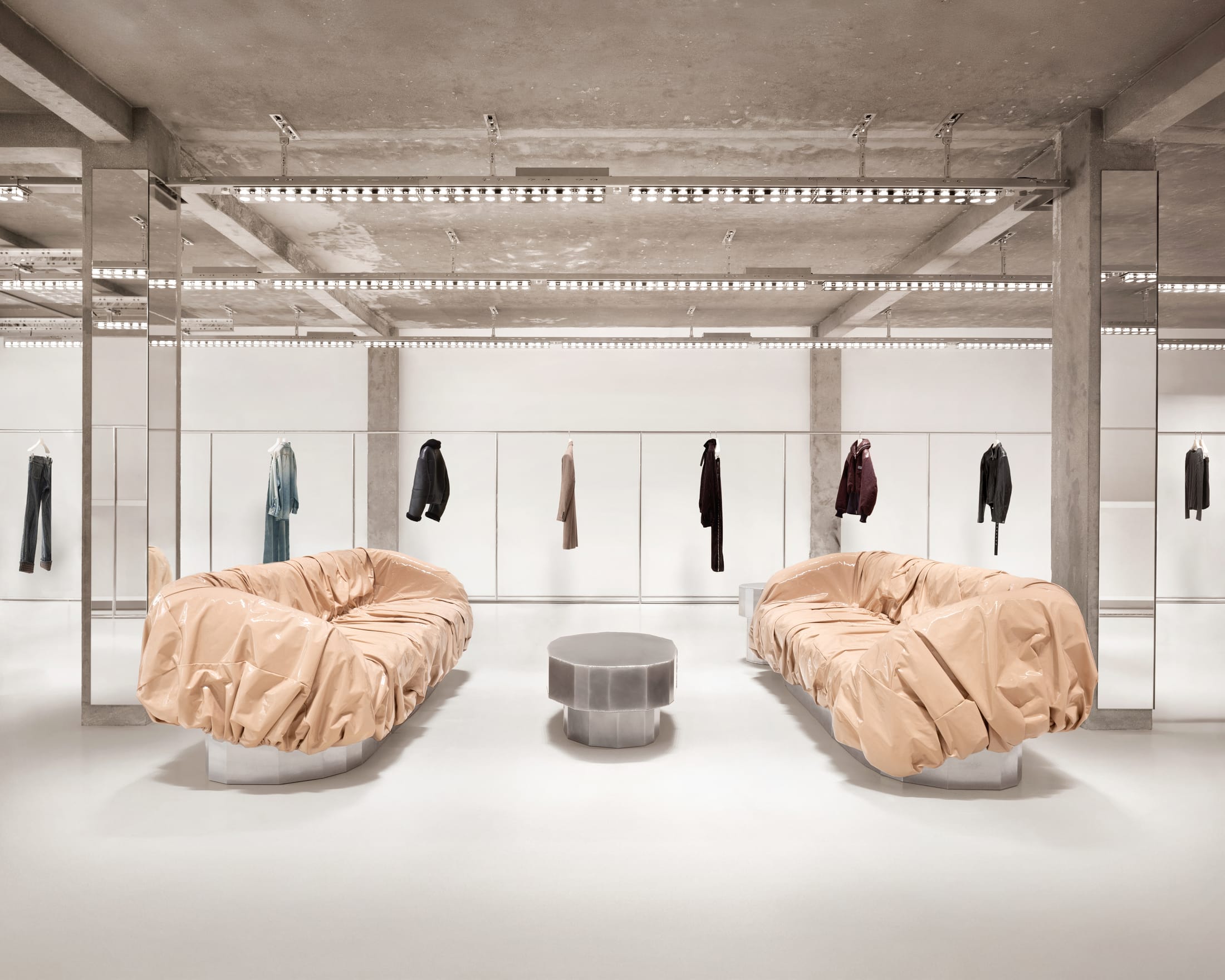 A showroom space featuring raw concrete columns and designer furniture.