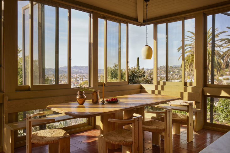 A dining area with large windows shaded by operable redwood screened panels.