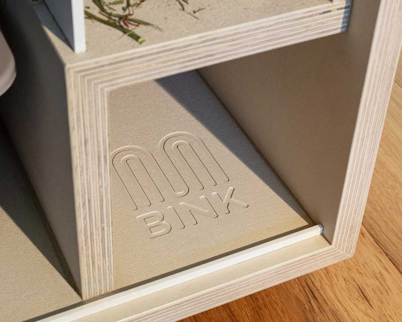 A close-up of a brand logo engraved into the corner of a wooden rabbit bench.