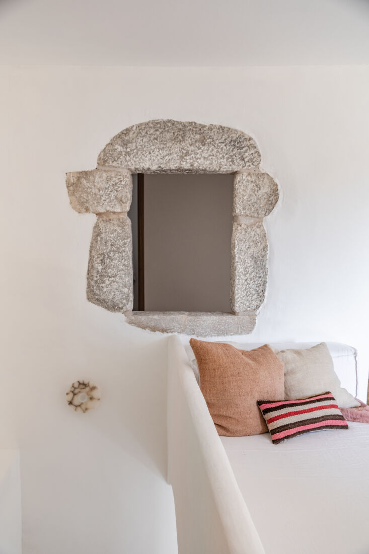 A cozy built-in seating nook next to an original stone window frame at the top of a staircase.