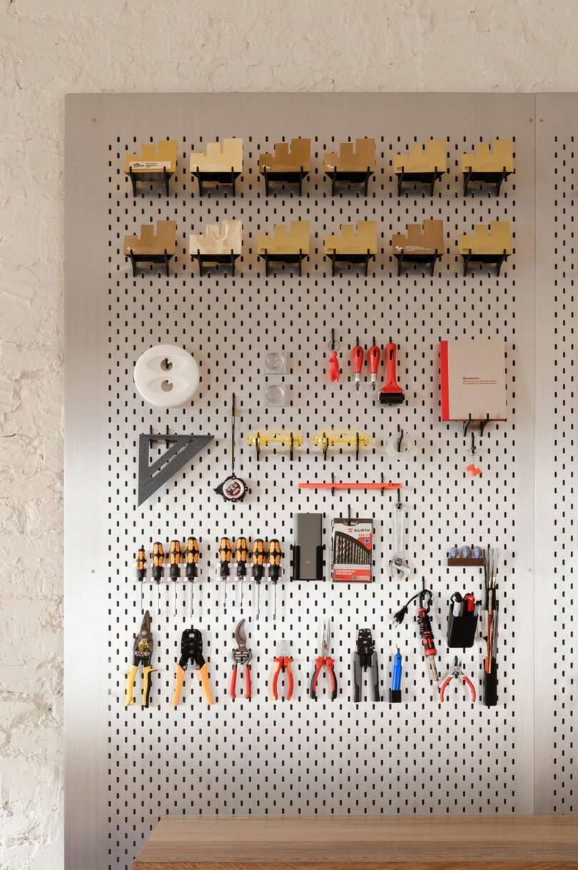 A metal pegboard wall with neatly organized hand tools, pliers, and rulers.