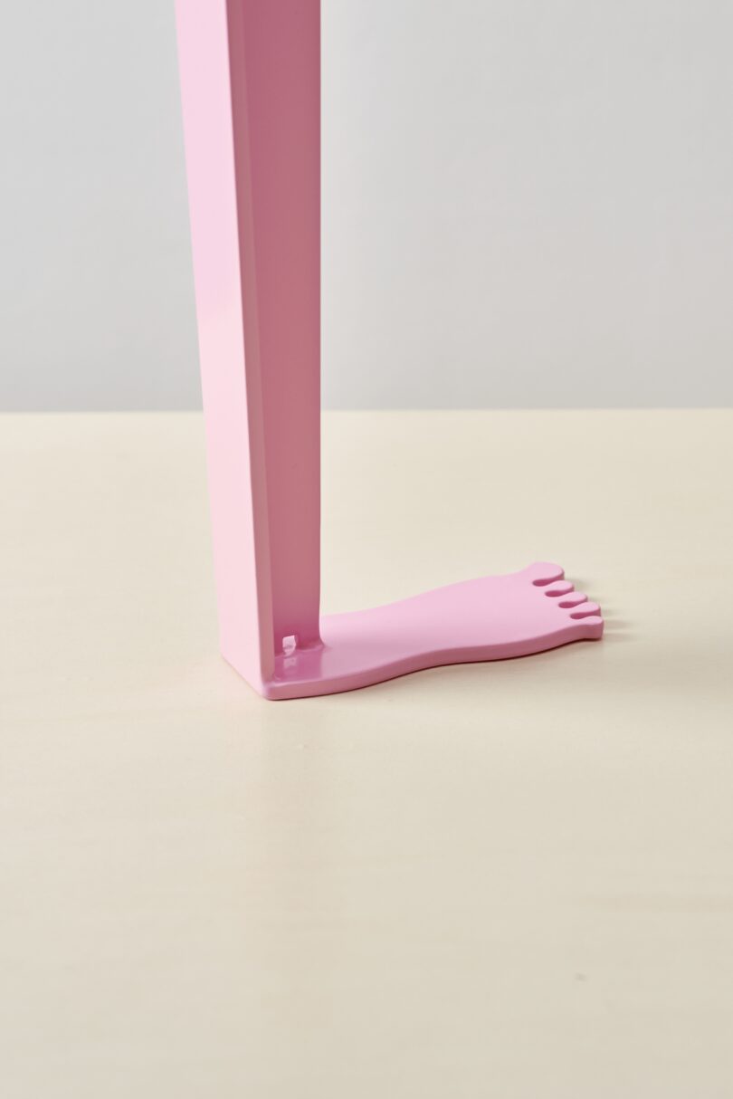 Close-up of a pink Tiptoe table leg featuring a base shaped like a human foot.