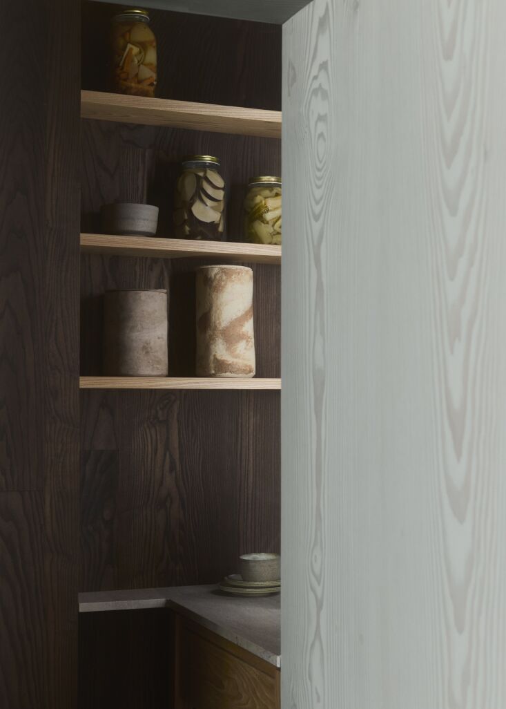 The pantry interior featuring dark oil-finished wood, shelves of pickled vegetables, and ceramics.