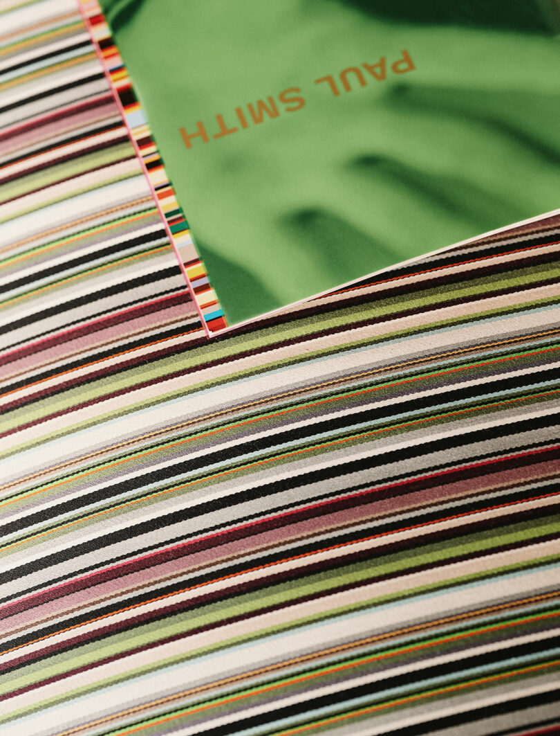 A Paul Smith branded booklet resting on vibrant striped upholstery.