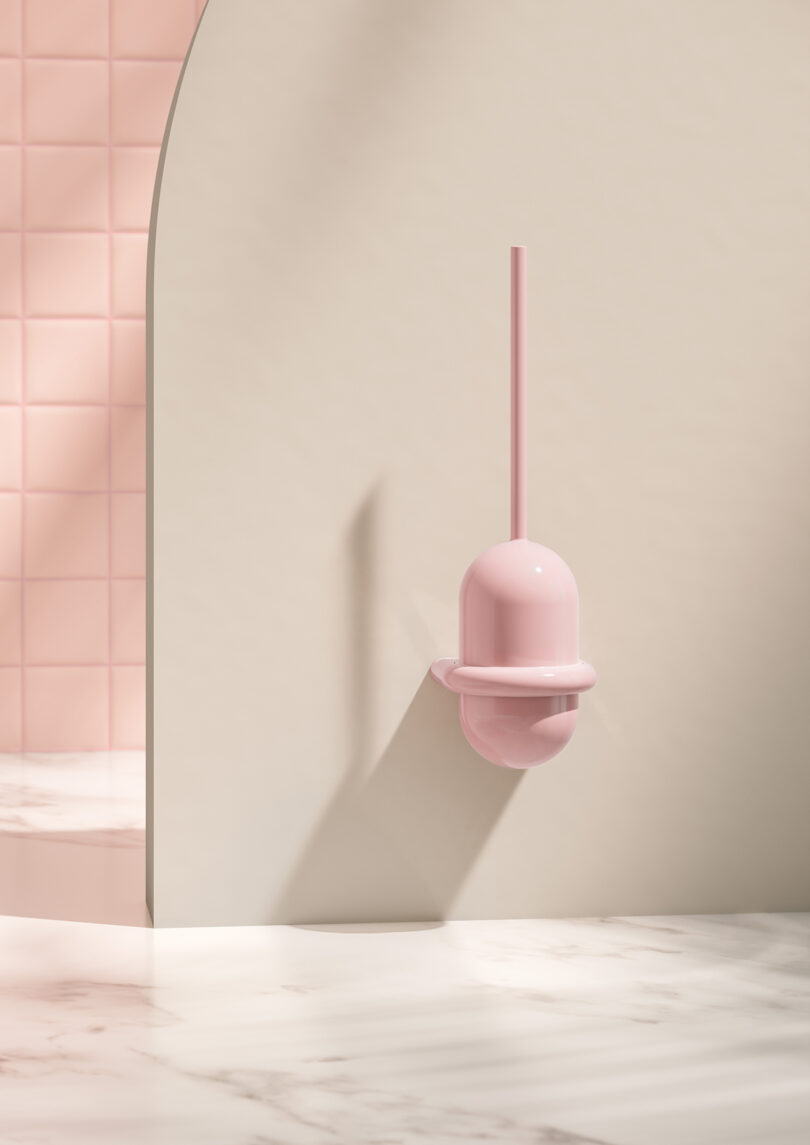 A pink toilet brush holder mounted on a light-colored wall with pink tiles and marble flooring.