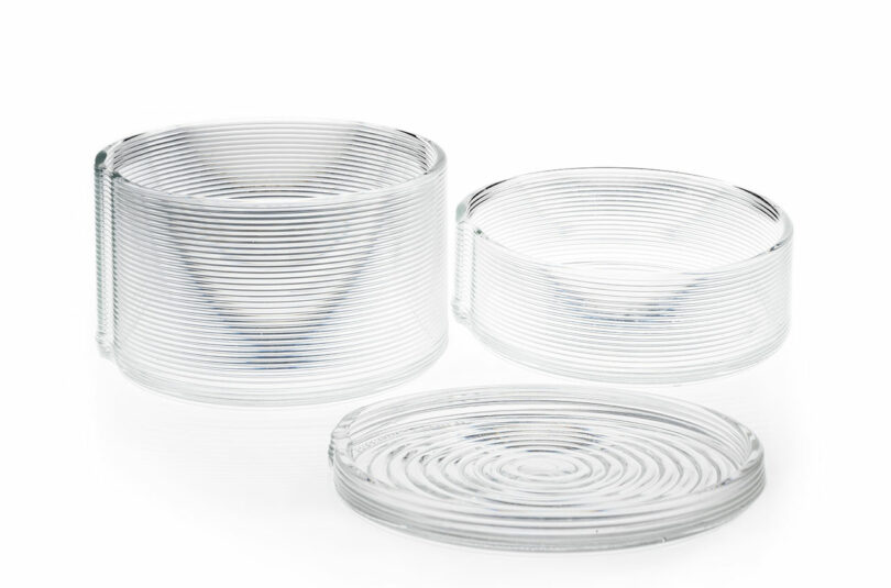 Three clear glass vessels of different heights with uniform horizontal ridges arranged on a white background.