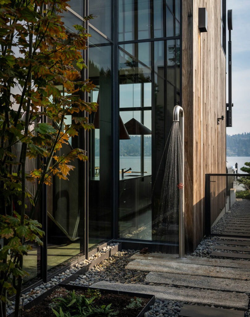 Outdoor shower area with a curved metal fixture and lake views in the background.