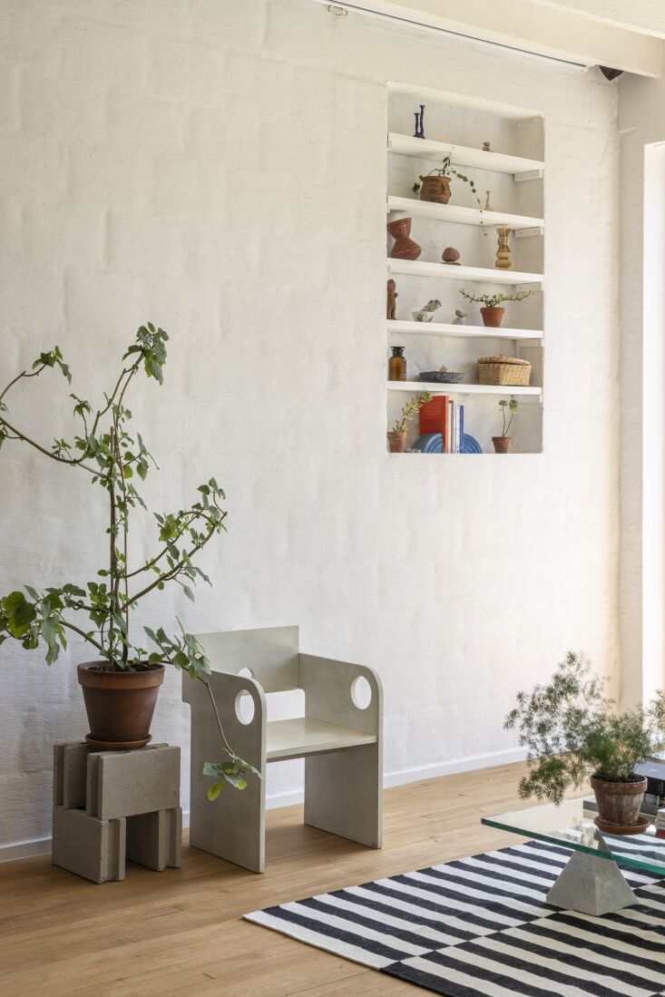 A close-up of a white-painted brick wall with integrated shelving and a thin layer of plaster.
