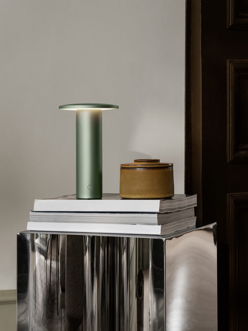 A green Solae lamp resting on books atop a metallic surface.