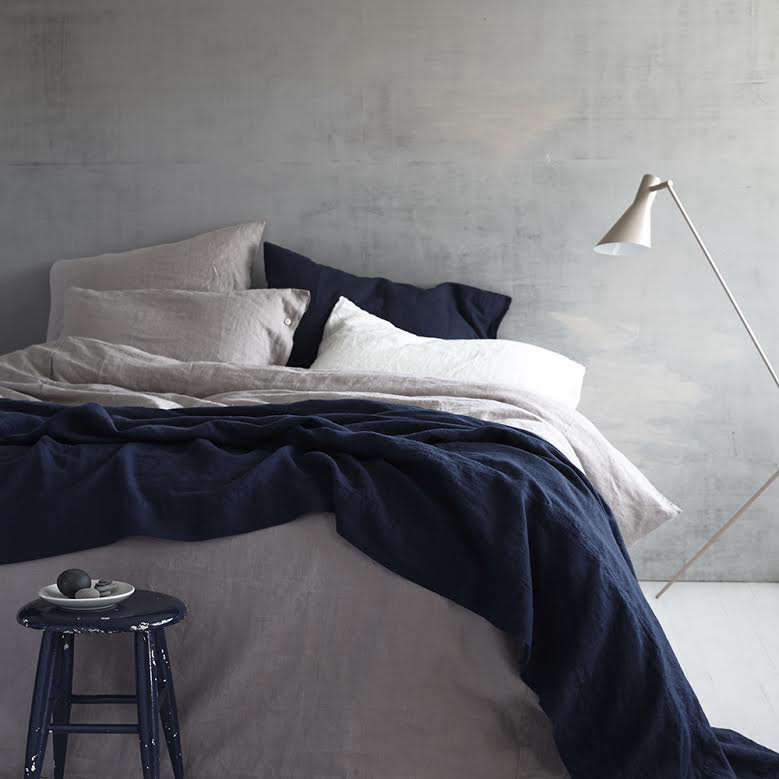 A bed featuring a mix of charcoal grey and rosy-hued dusk linen bedding.