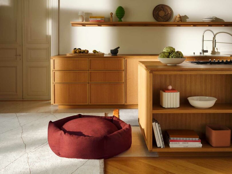 A vibrant red circular Luoto dog bed positioned in a minimalist, modern living room.