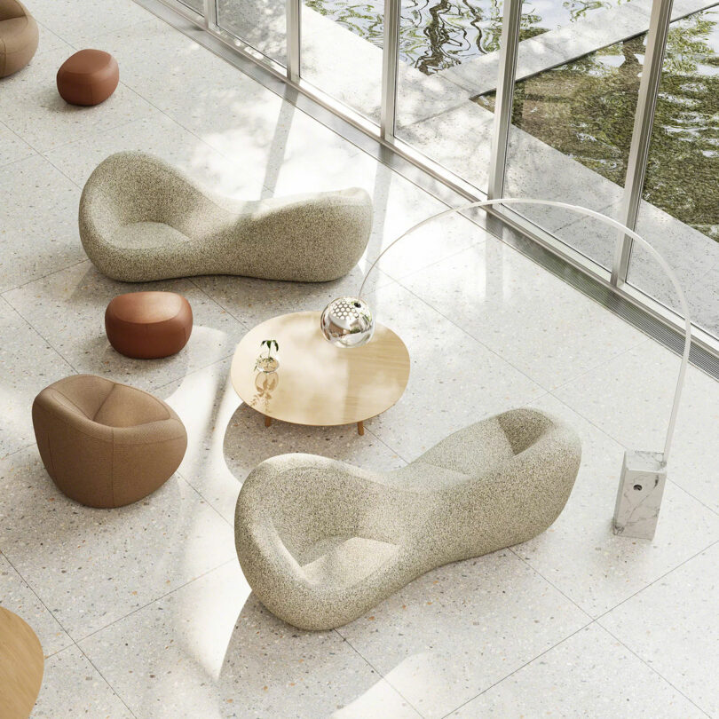 Modern lounge area with curved beige sofas and floor-to-ceiling windows overlooking a reflecting pool.