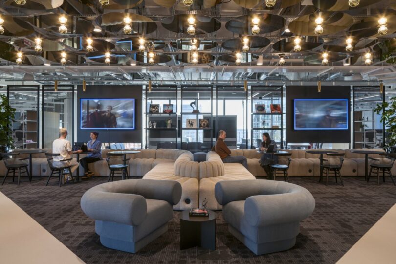 A lounge area with curved sofas and modern overhead lighting in the Virgin Media O2 office.