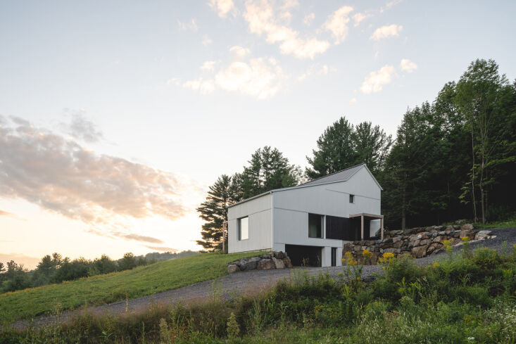 The house nestled into the mountain slope with a roofline that mirrors the natural incline of the terrain.