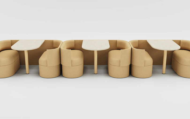 A row of beige booth-style modular seating units with integrated tables for collaborative work.