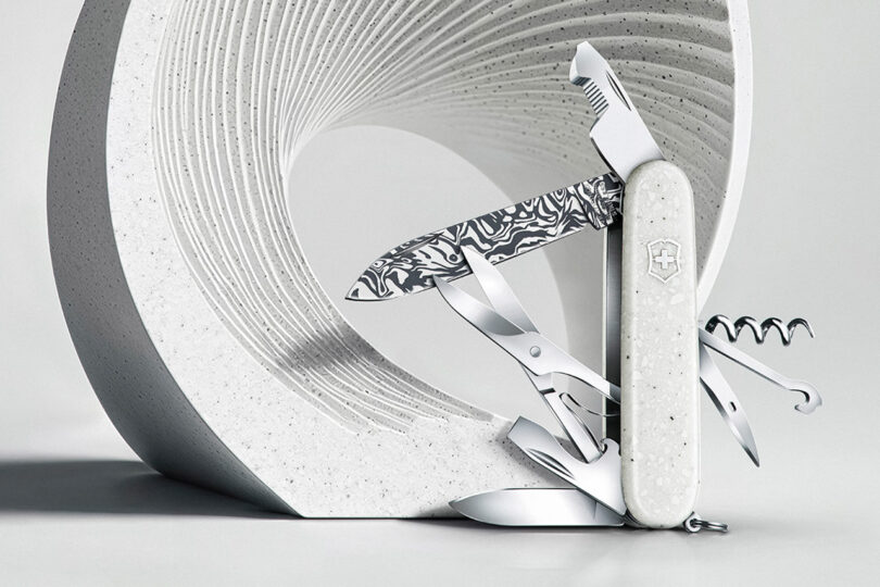 Victorinox knife with tools extended posed in front of a modern white textured sculpture.
