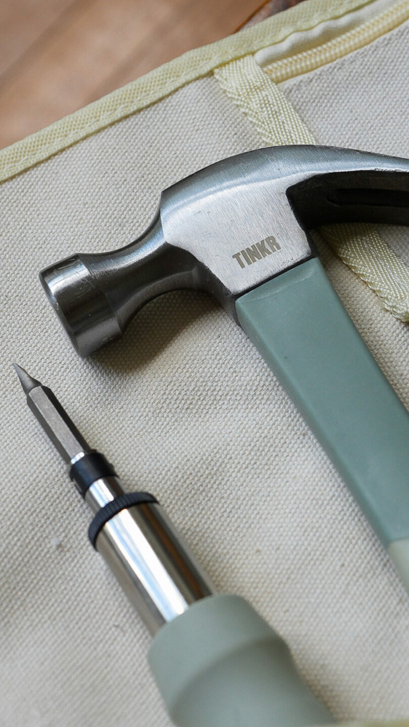 A close-up shot of a hammer and screwdriver featuring ergonomic sage green handles.
