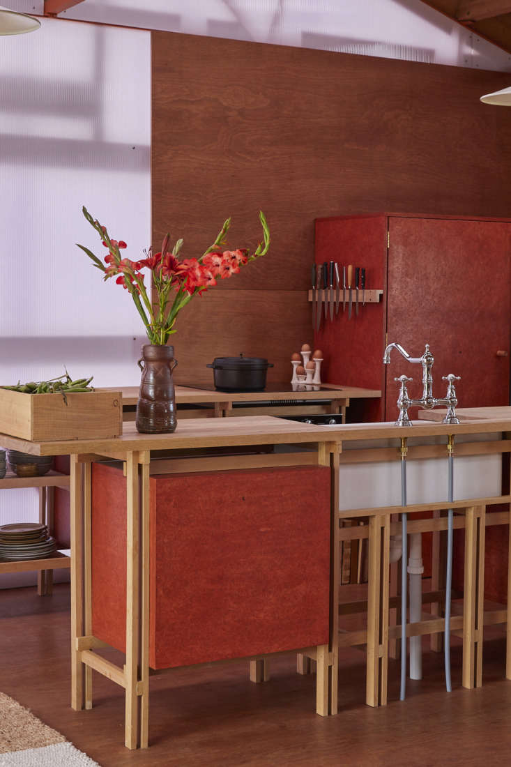 Modern kitchen with dark timber frames, stained strand board cabinets, and oak counters inside the shed.