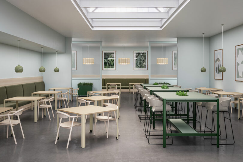 A bright office cafeteria and lounge area with light wood furniture, botanical wall art, and a large skylight.