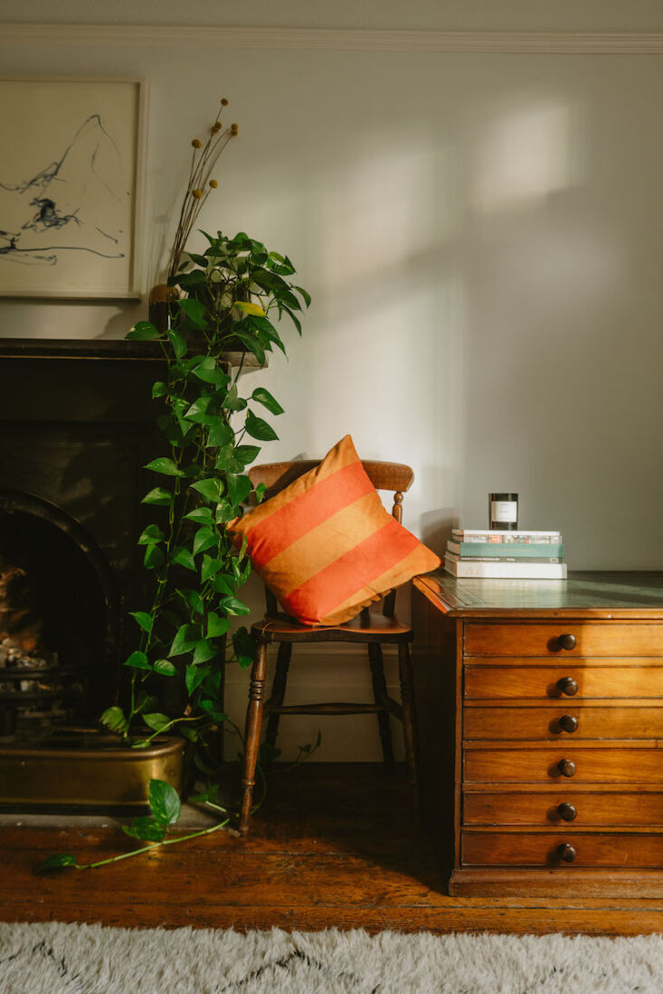 A square cushion with brown and yellow stripes on a neutral chair.
