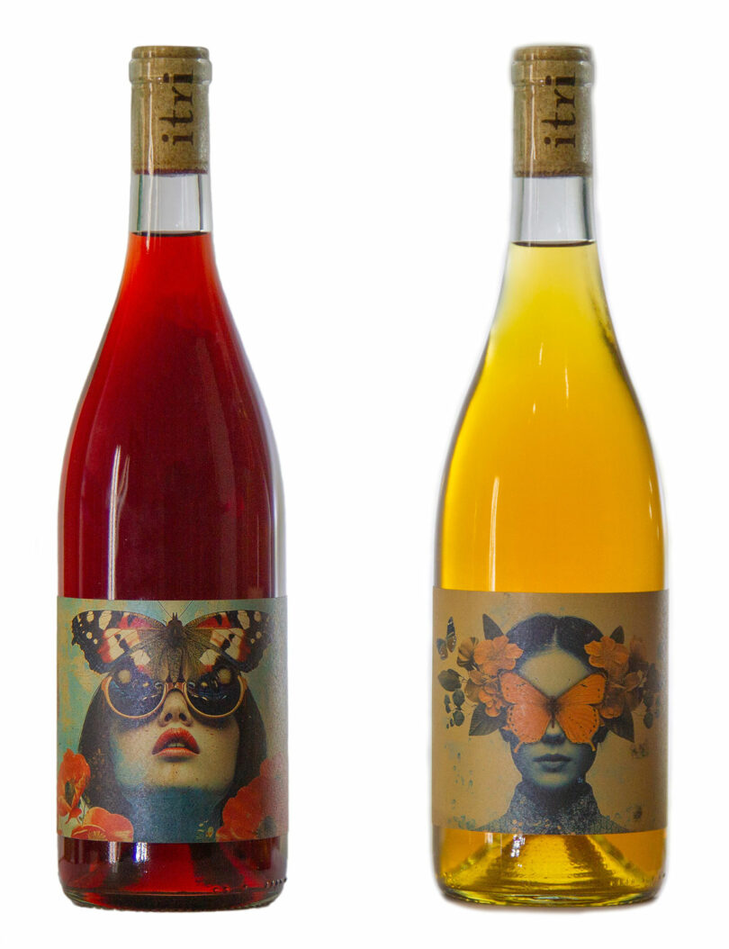 Two wine bottles with artistic labels featuring female faces and butterfly motifs, one red and one golden.
