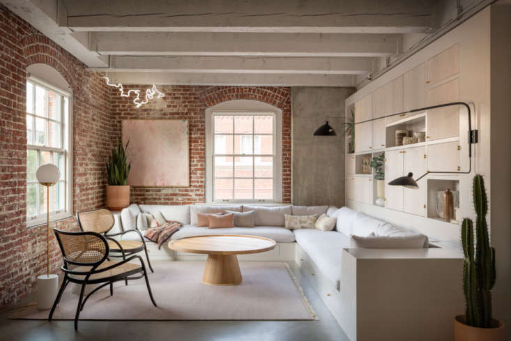 A low-profile built-in sofa in a loft featuring large wooden pull-out drawers underneath the cushions.