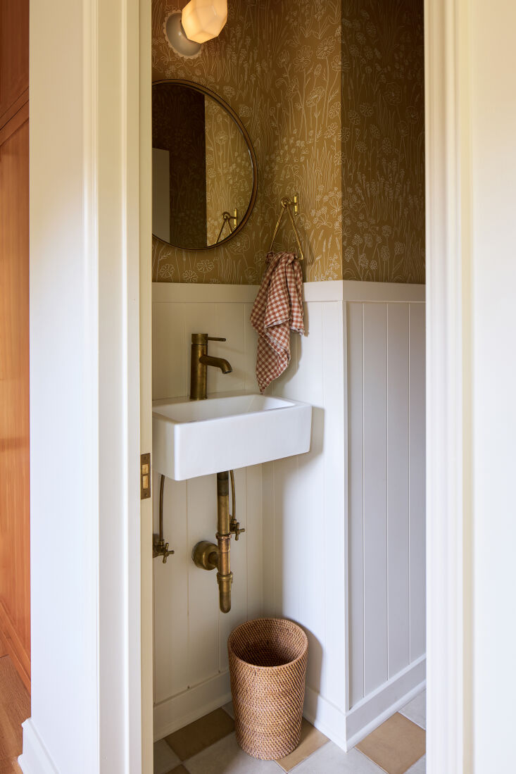 A small powder room with floral wallpaper and a white wall-hung basin.