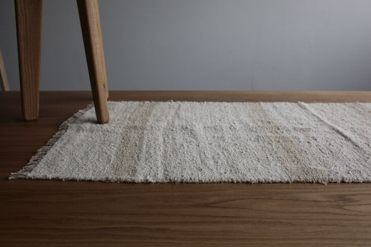 A long, textured vintage hemp runner rug on a tiled floor.