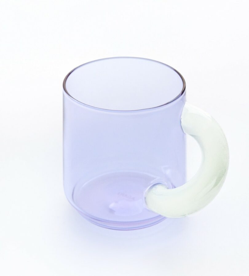 A transparent light purple glass mug with a curved white handle.