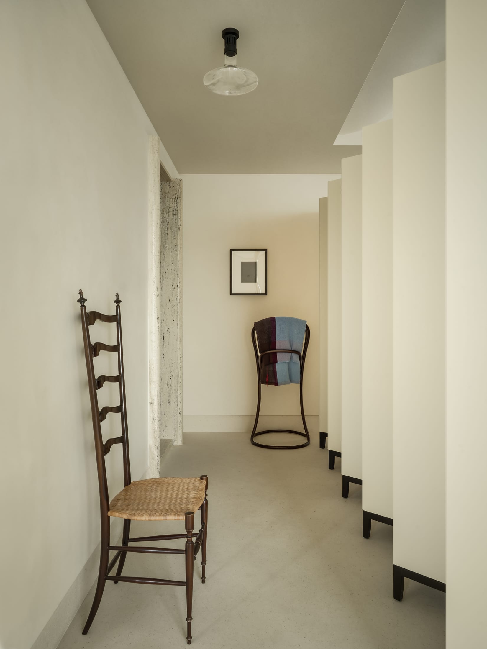 A wide shot of a minimalist luxury interior with marble walls framing a view of a central courtyard.