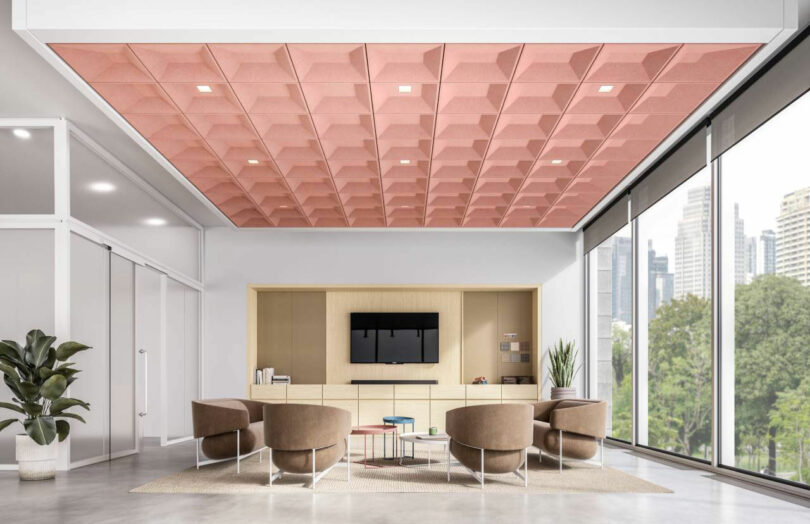Modern office lounge with pink geometric acoustic ceiling panels and a city view.