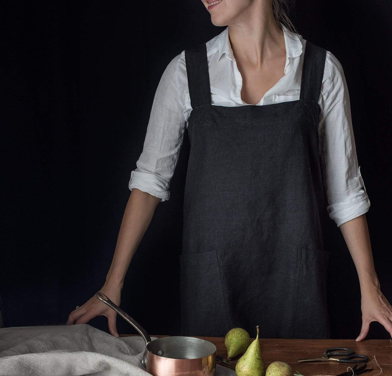 A model wearing a charcoal-colored heavyweight linen pinafore apron.